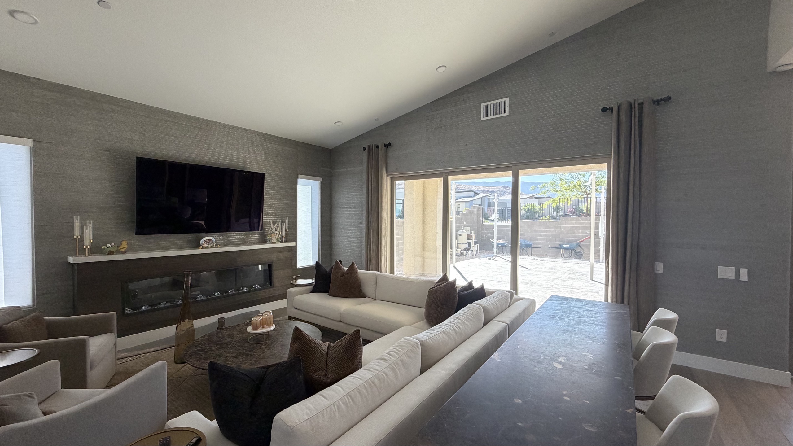Living room with grey grasscloth wallcovering, drapery, and fireplace
